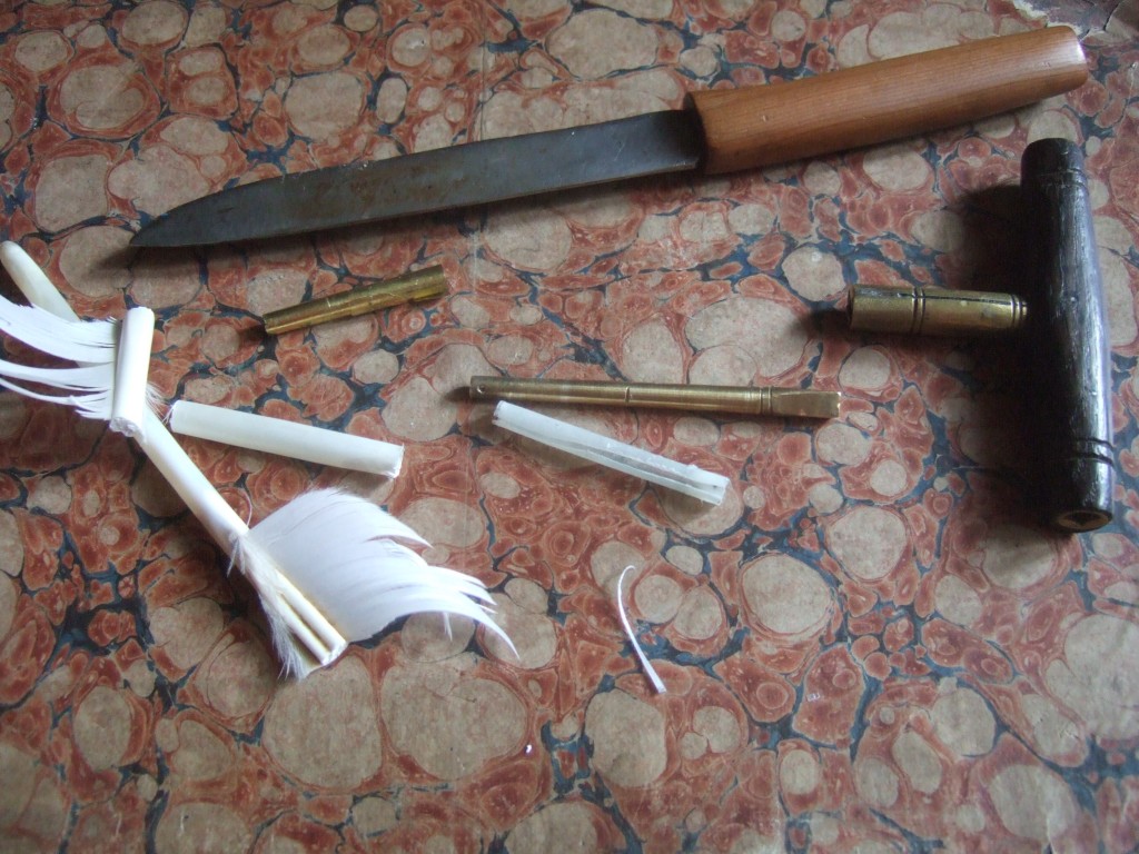 Goose quills to the left; the scraped seagull quill with the pin in the centre, the old brass sheet shim above.